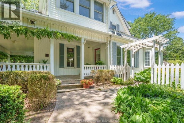 Close-up of the white house porch with wood flooring, white railings, and a pergola. - 38 Harold Street South, Ridgetown