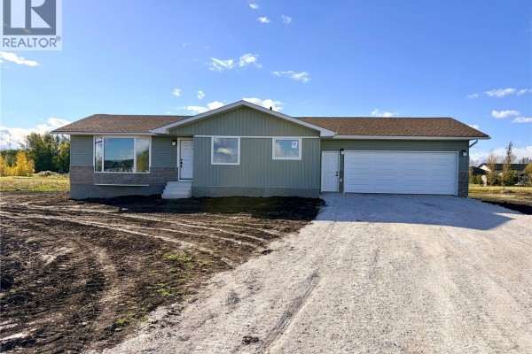Front view of a light green house with a stone base, large windows, and a double garage. - 38 Heritage Cove, Rosthern Rm No  403