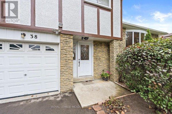 Detail of the house entrance with a garage, front door, and stone pillar. - 38 Jasper Crescent, Brampton