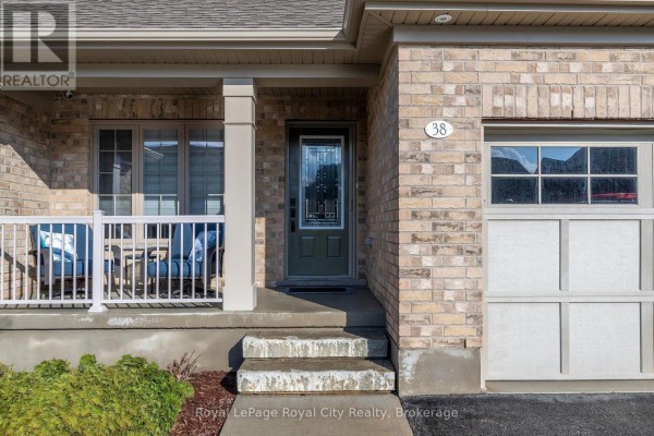 Front door and porch area of a townhouse with stone steps and light beige brick. - 38 Juniper Street, Guelph/eramosa