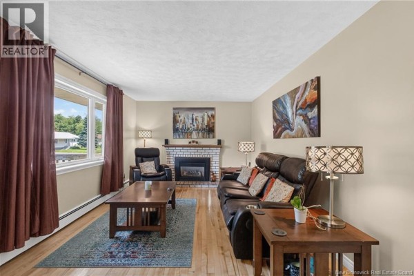 Living room with leather furniture, a fireplace, wood floors, and a large window overlooking the yard. - 38 Lindsay Street, Riverview