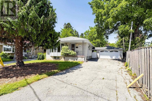 Exterior of a modest brick bungalow with a detached garage and mature trees on a sunny day. - 38 Lombardy Crescent, Toronto