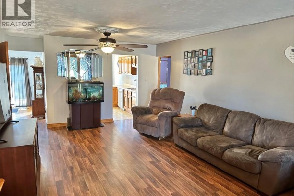 Living room showing sectional sofa, recliner, aquarium, and view towards the kitchen area. - 38 Mann Avenue, Simcoe