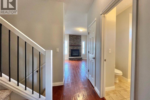 View of hallway with stairs, fireplace, and doorway to bathroom with toilet. - 38 Mckenzie Lane, White City