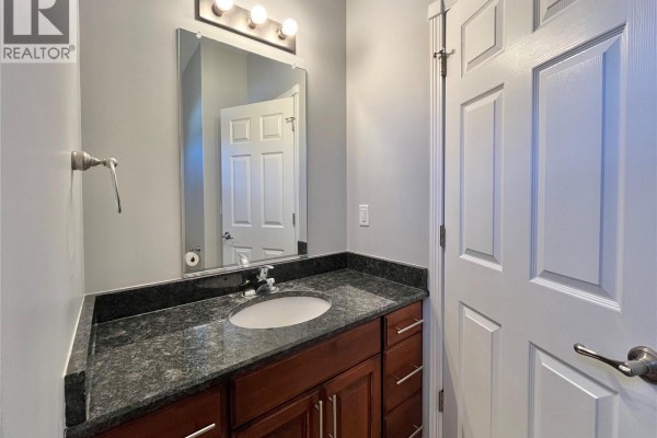 Powder room with gray walls, granite countertop vanity, and mirror above sink. - 38 Mckenzie Lane, White City