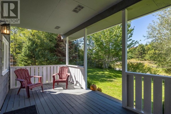 View from the covered porch looking out to a green lawn and trees. - 38 Post Road, Chezzetcook