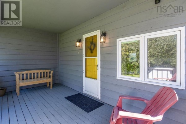 Covered front porch with a wooden bench, red chairs, and a yellow front door. - 38 Post Road, Chezzetcook