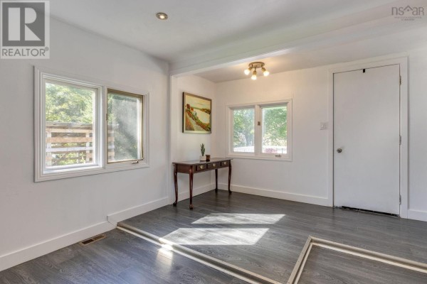 Interior room with white walls, dark laminate flooring, and a wooden console table. - 38 Post Road, Chezzetcook