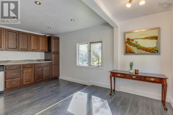 Open-concept interior showing dark wood kitchen cabinets, granite countertops, and a dining area. - 38 Post Road, Chezzetcook