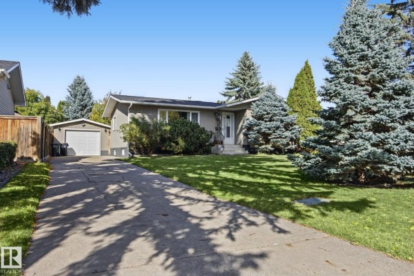 Wide angle exterior view of a grey bungalow with a long driveway and lush green lawn. - 38 Raven Dr, Sherwood Park