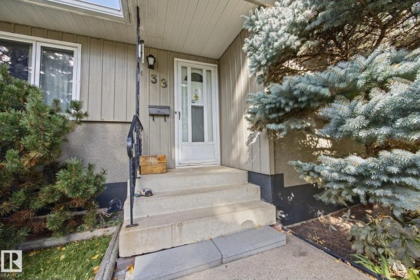 Front door entrance with concrete steps, metal railing, and address number 38. - 38 Raven Dr, Sherwood Park