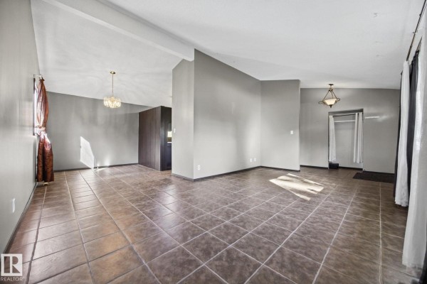 Open concept living and dining area with tan tile floors and neutral walls. - 38 Raven Dr, Sherwood Park