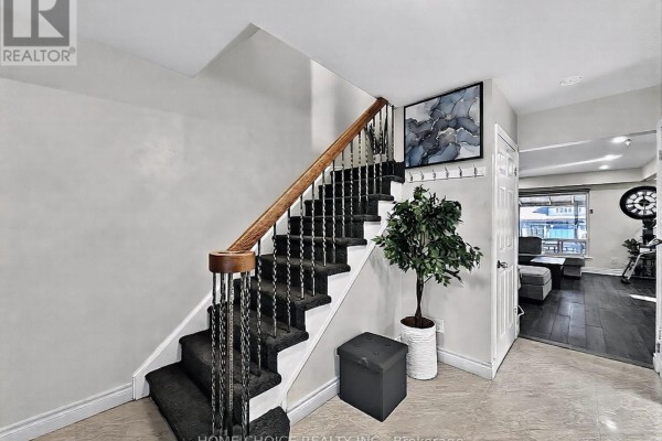Bedroom with dark wood floor, queen bed, desk with dual monitors, and a large mirror. - 38 Robbinstone Drive, Toronto