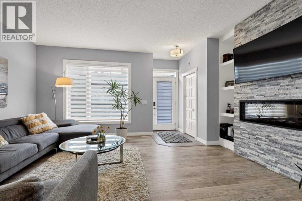 A living room with a television above a fireplace, flanked by built-in white shelves. - 38 Sage Bluff Gate Nw, Calgary