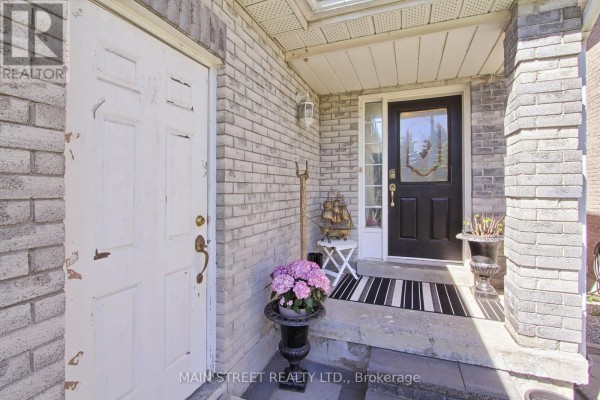 Close-up of the front entrance featuring a white door, black door with glass insert, and potted flowers. - 38 Sundew Drive, Barrie