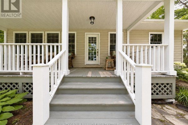 View from the bottom of the front porch steps, showing white railings, a door, and windows. - 38 Westview Drive, Kawartha Lakes