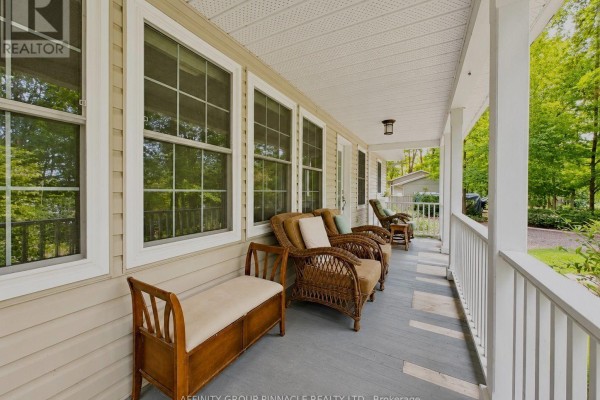 Wicker chairs and a wooden bench on a covered front porch with large windows and siding. - 38 Westview Drive, Kawartha Lakes