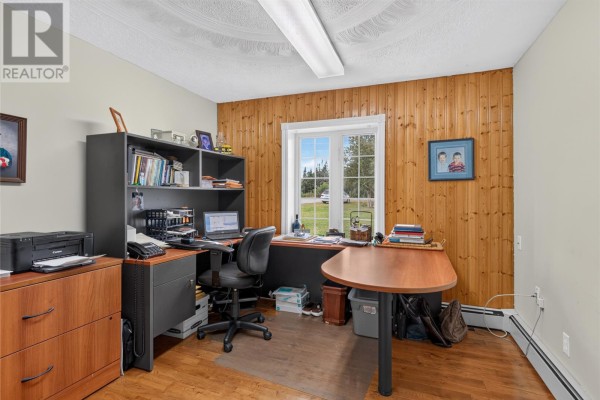 Home office with wood-paneled walls, a desk with computer equipment, and a window view. - 380-380a Gander Bay Road, Gander