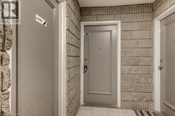 Hallway with a unit 208 door, stone tile walls, and grey doors. - 380 Admiral Drive Unit# 208, London