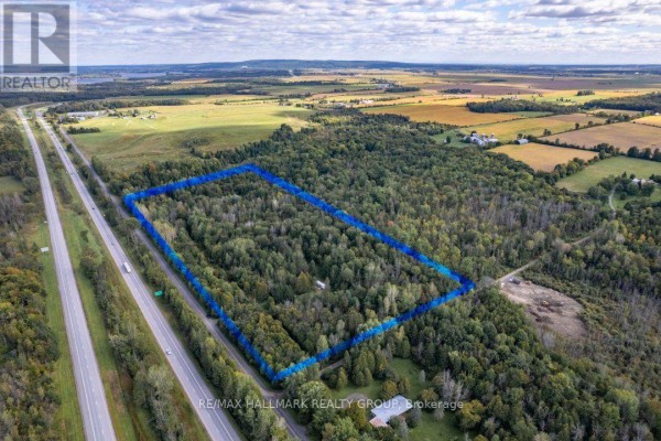 Drone view of a large, wooded property outlined in blue, next to a highway. - 380 Concession 1 Road, East Hawkesbury