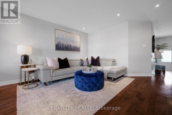 Living area with sectional sofa, blue ottoman, textured rug, and decorative pillows. - 380 Goldenbrook Way, Ottawa