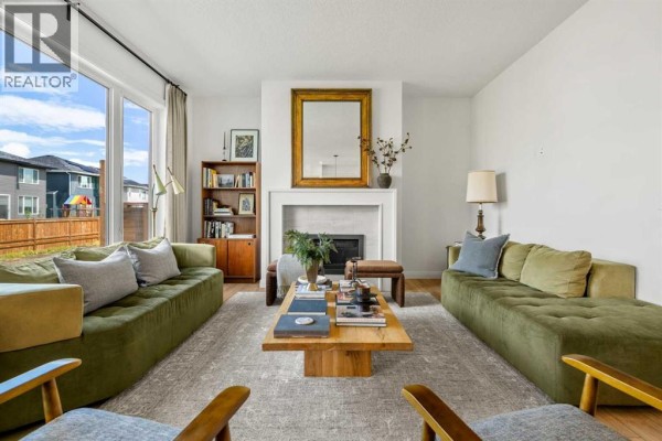 Living room with a large window, fireplace, built-in bookshelf, and two green sectional sofas. - 380 Northern Lights Green, Langdon