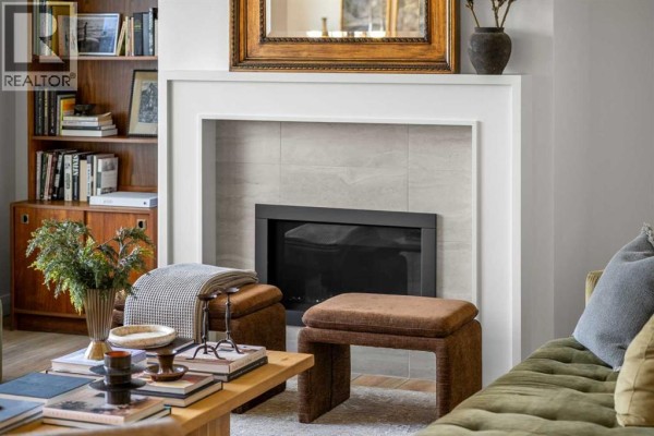 Close-up of a modern fireplace with tile surround, flanked by upholstered ottomans and a wooden coffee table. - 380 Northern Lights Green, Langdon