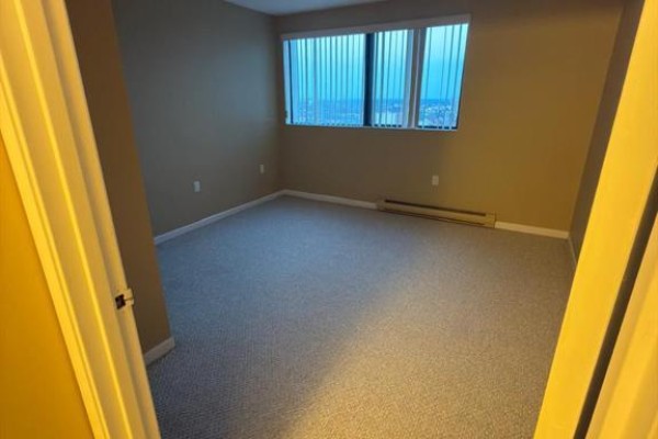 Bedroom with beige carpet, beige walls, and a large window with blinds and a view. - 380 Pelissier Street Unit# 2402, Windsor