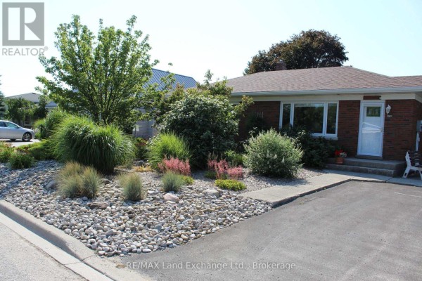 Front yard landscaping with rocks, ornamental grasses, and mature trees. - 380 Princes Street S, Kincardine