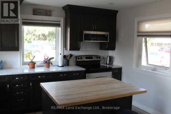 Kitchen with dark cabinets, white subway tile backsplash, stainless steel appliances, and island. - 380 Princes Street S, Kincardine