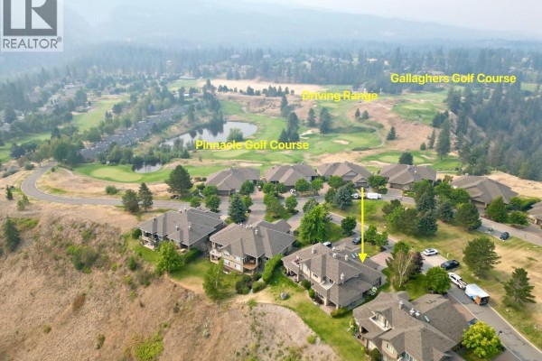 Aerial view of townhouses on a hillside overlooking a valley, with a yellow arrow pointing to unit 29. - 3800 Gallaghers Pinnacle Way Unit# 29, Kelowna