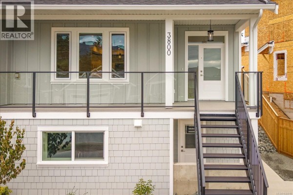 Close-up of duplex entrance with number 3800, white door, glass sidelight, and outdoor lighting. - 3800 Marjorie Way, Nanaimo