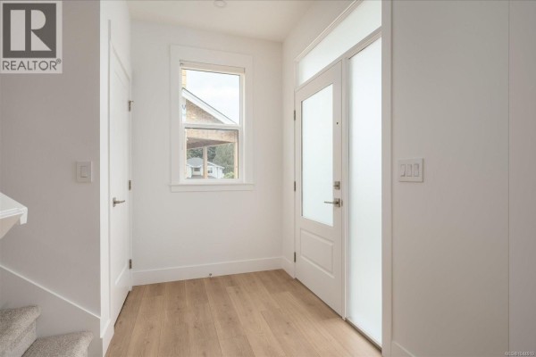 Interior entrance foyer with white walls, light wood flooring, and a frosted glass door. - 3800 Marjorie Way, Nanaimo