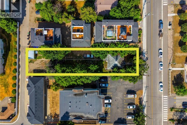 Rear yard view with a lawn, trees, a concrete pathway, and a pickup truck on the right. - 3802 32 Avenue, Vernon