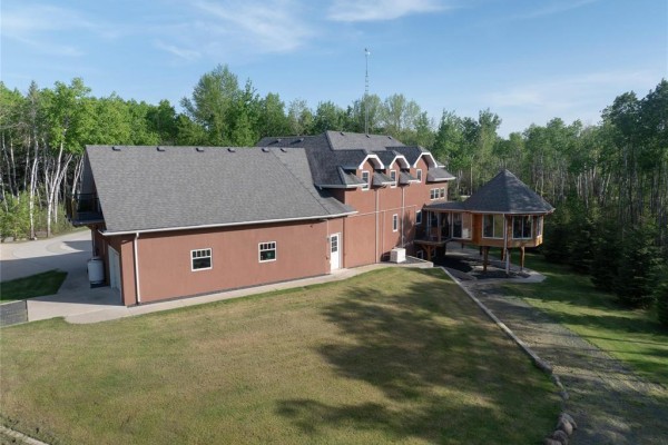 Aerial view of a large, red two-story house with a grey roof, surrounded by mature trees. - 38047 38n Road, Ste Anne Rm
