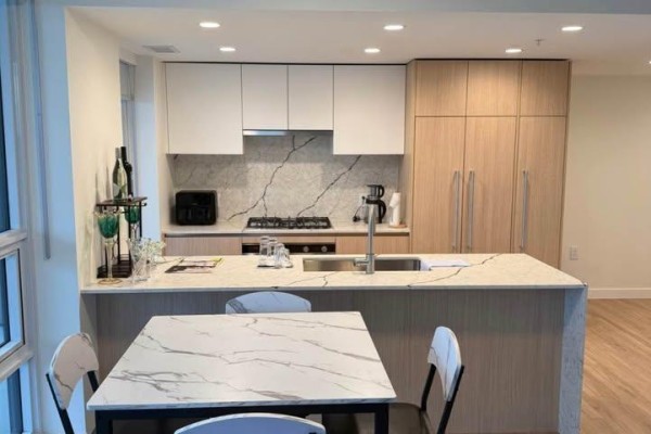 Kitchen with white and wood cabinets, gas range, and island seating. - 3805 2135 Springer Avenue, Burnaby