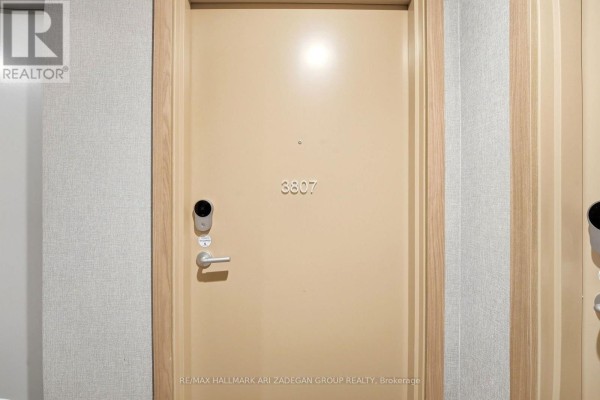 Apartment entrance door labeled 3807 with a keyless entry system and light wood trim. - 3807 - 1 Quarrington Lane, Toronto