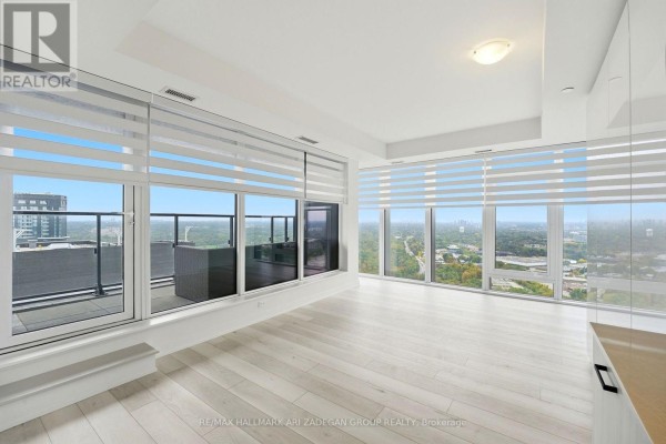 Living room with large windows, roller blinds, and light wood flooring with city views. - 3807 - 1 Quarrington Lane, Toronto