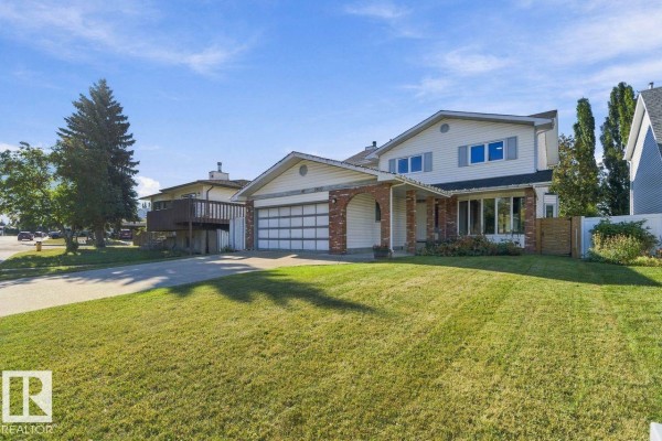 Side view of the house showing a lawn, driveway, and the front exterior with a covered porch. - 3807 36 Av Nw, Edmonton
