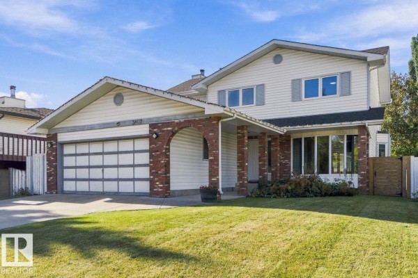 Front exterior of a two-story house with white siding, brick accents, and a two-car garage. - 3807 36 Av Nw, Edmonton