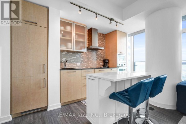 Kitchen with light wood cabinets, granite countertops, stainless steel appliances, and island with bar stools. - 3808 - 14 York Street, Toronto