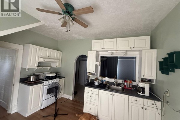 Kitchen with white cabinets, white stove, black countertops, and a ceiling fan. - 381 Main Street, Bengough