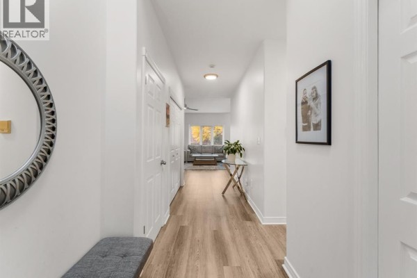 Hallway with white walls, light wood-look flooring, and double doors leading to a living area. - 381 Tuscany, Tecumseh