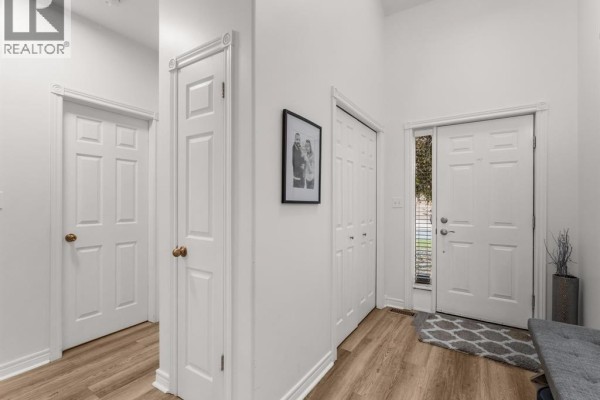 Interior view of a hallway with white doors, a framed picture, and a front door. - 381 Tuscany, Tecumseh