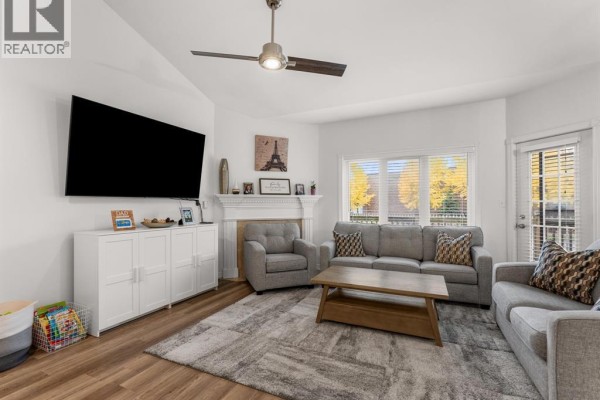 Living room with grey sofas, a white media console, a fireplace, and a ceiling fan. - 381 Tuscany, Tecumseh