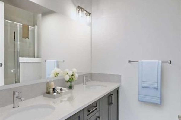Bathroom with a double vanity, grey cabinets, quartz countertops, and a large mirror. - 381 Waterford Boulevard, Chestermere