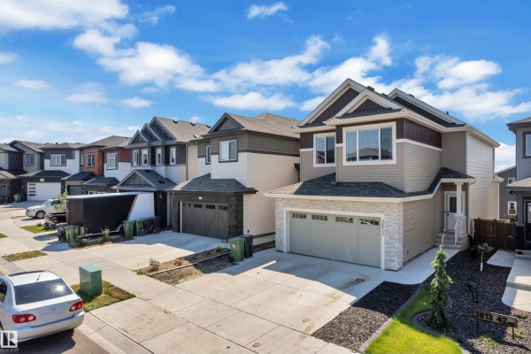 Front exterior of a beige and brown two-story house with a stone accent facade and a double garage. - 3811 42 Av, Beaumont