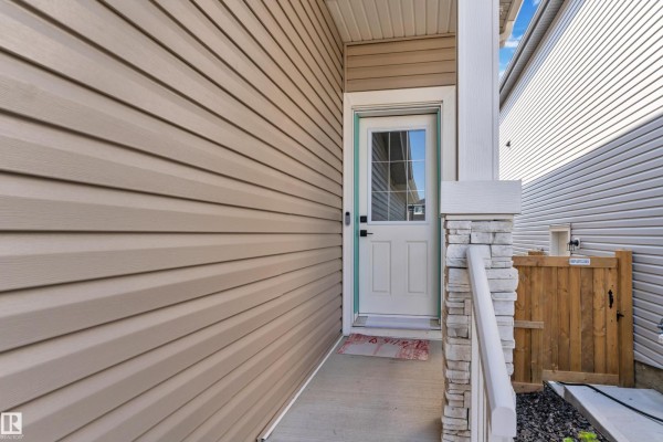 Close-up of the side entrance to a house with beige vinyl siding and a glass-paneled door. - 3811 42 Av, Beaumont