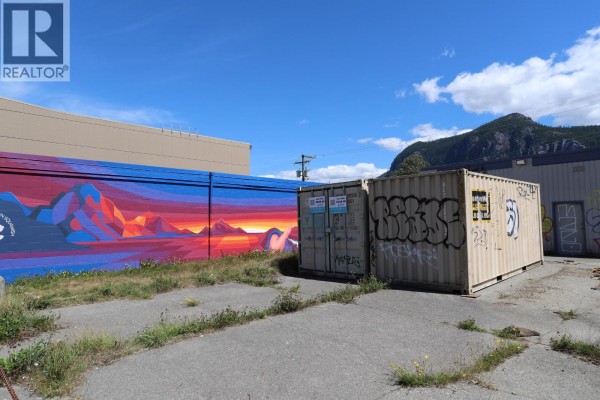 Exterior of a building with two garage doors covered in graffiti, on a cracked concrete lot. - 38120 Cleveland Avenue, Squamish