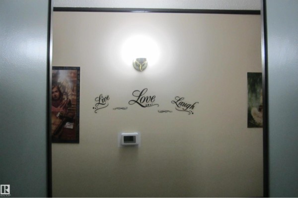 Wall with a thermostat, light fixture, and framed artwork flanking inspirational text. - 3814 37 Av, Leduc